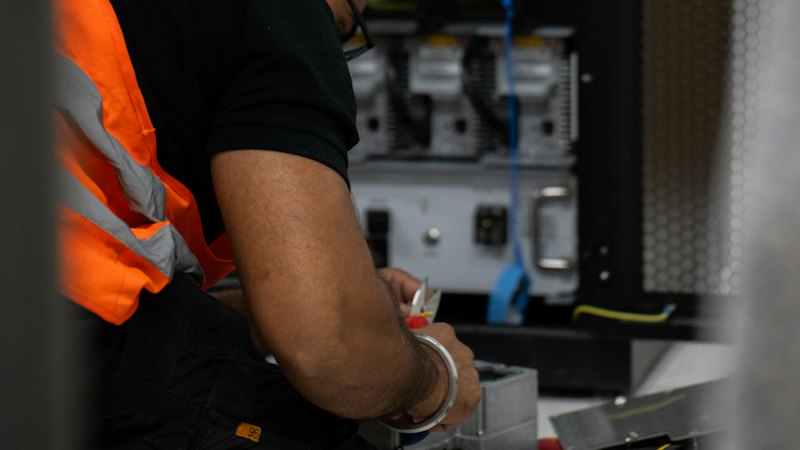 Technician in a hi-vis vest working on network equipment